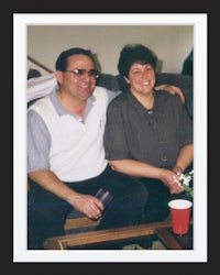 a man and woman smiling while sitting on a couch